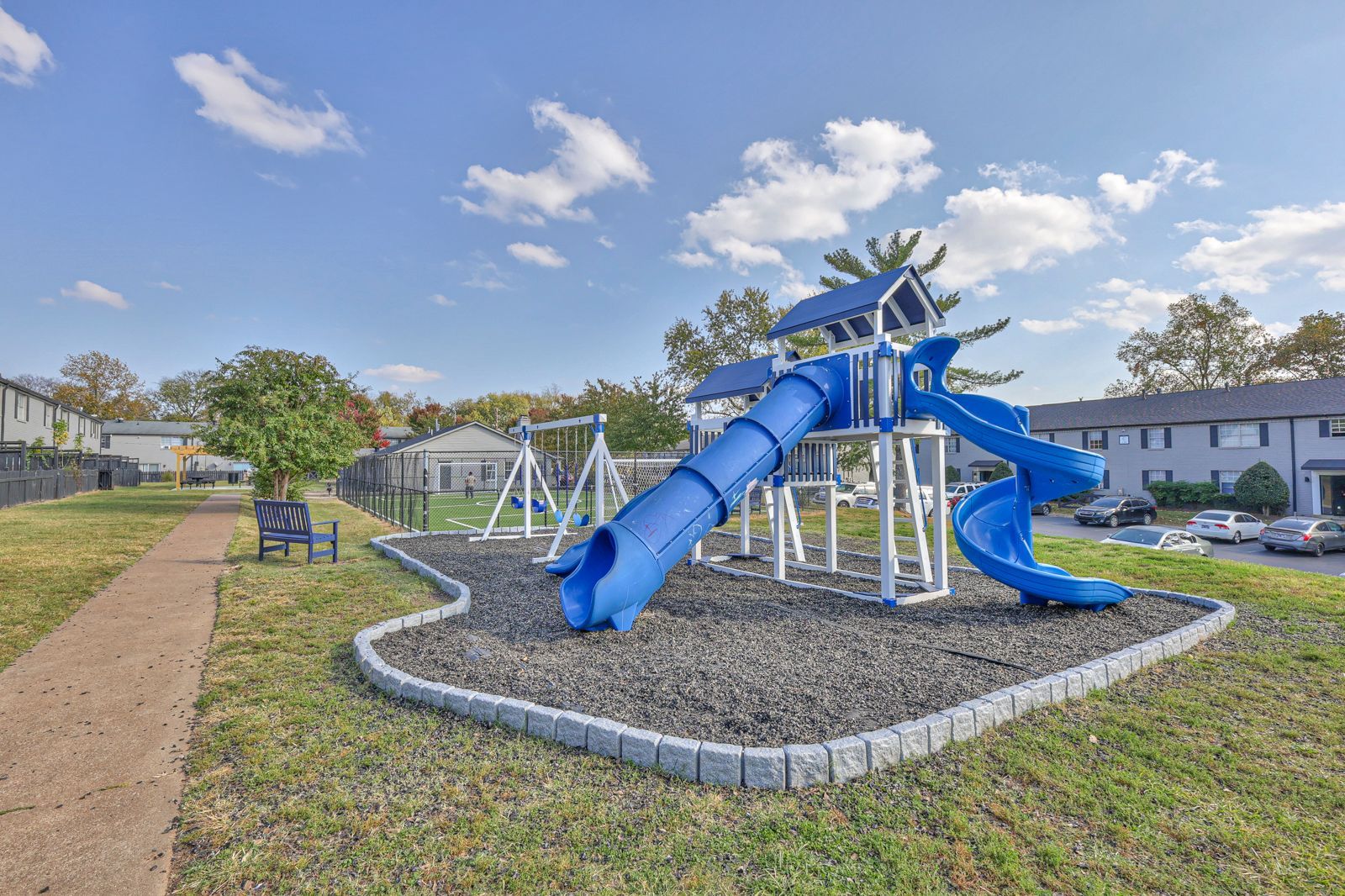 Photo of the community playground, showing a couple of slides, swings, and more