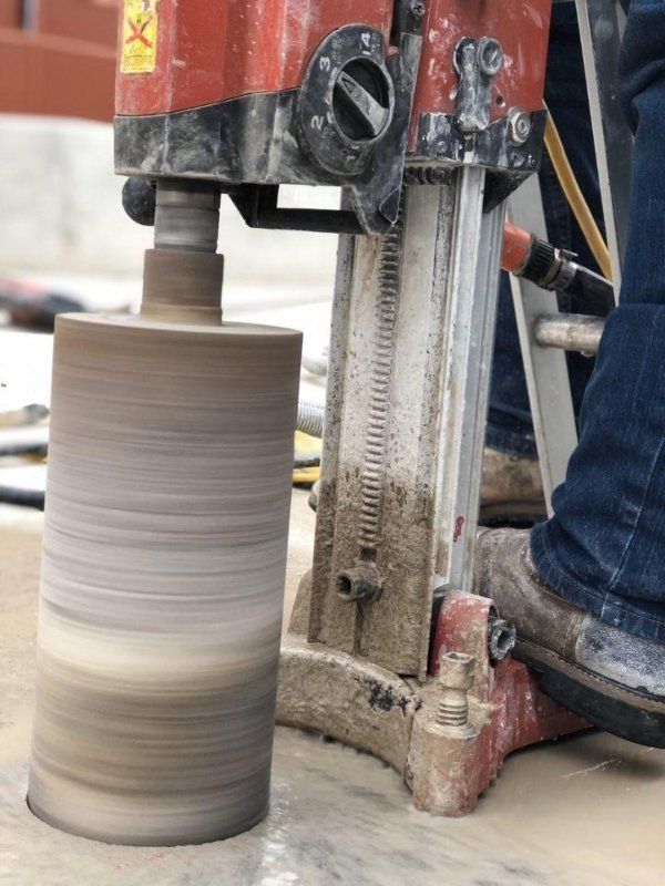 Pottery wheel shaping a tall clay cylinder beside a worker’s boot and machine stand