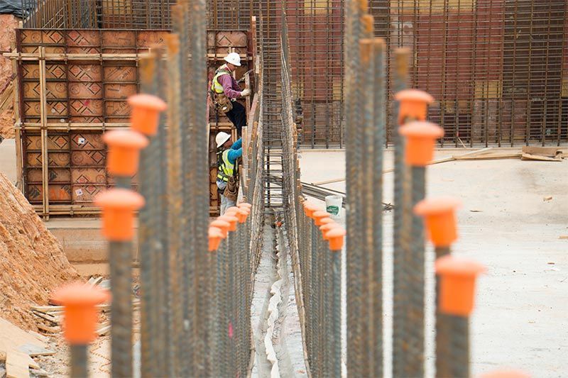 Construction site with rebar columns and workers near a concrete walkway