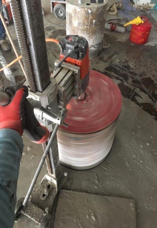Worker operates a machine wrapping a large cable spool in a workshop.