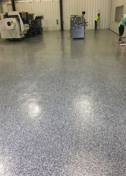 Empty industrial room with polished speckled floor and a few machines along the walls.
