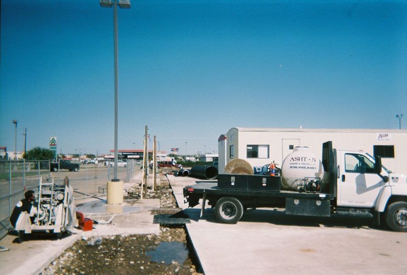Work truck at a roadside worksite with equipment and debris under a clear blue sky