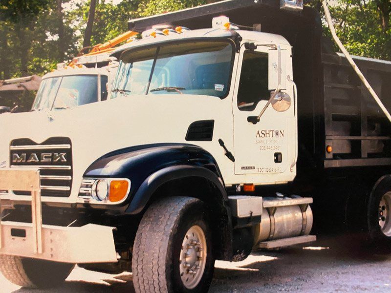 White and black dump truck parked on a street, front-left view