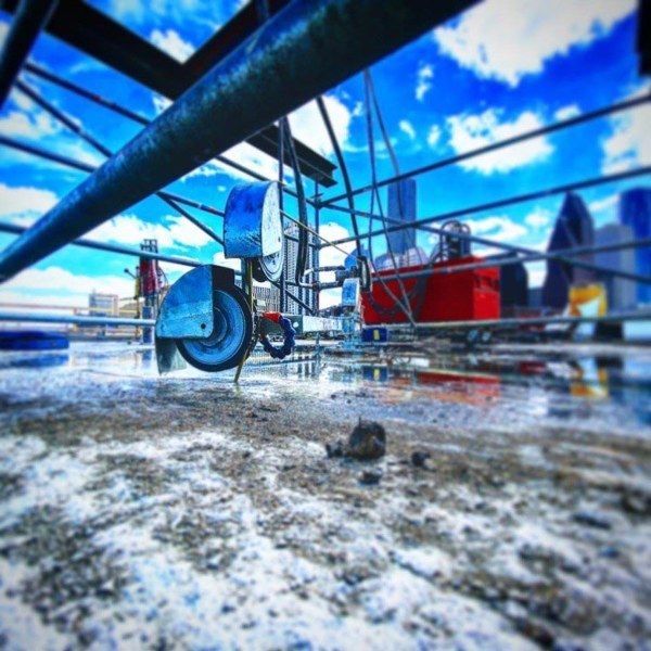 Empty shopping cart on a wet rooftop with blue sky and clouds in the background