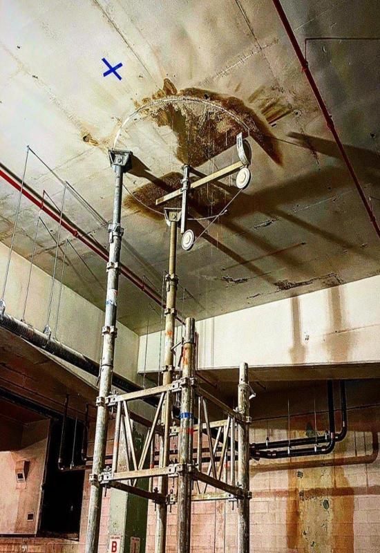 Scaffolding under a concrete ceiling crack in an unfinished industrial room