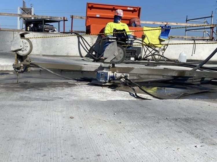 Workers repairing a damaged boat hull on a boat lift under a clear blue sky