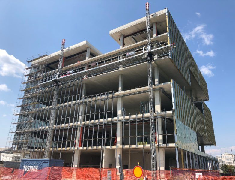 Partially built multi-story concrete building with scaffolding under a blue sky