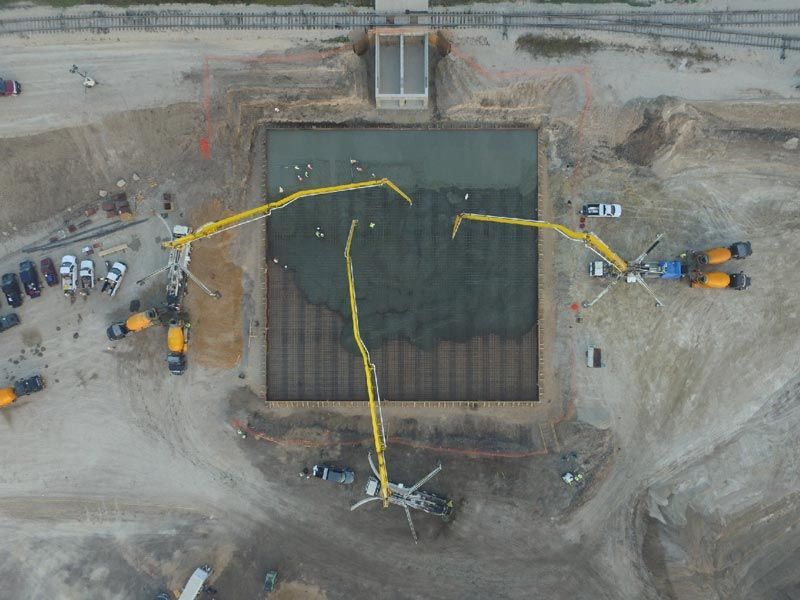 Aerial view of a construction site with a large square excavation and yellow excavators on both sides.