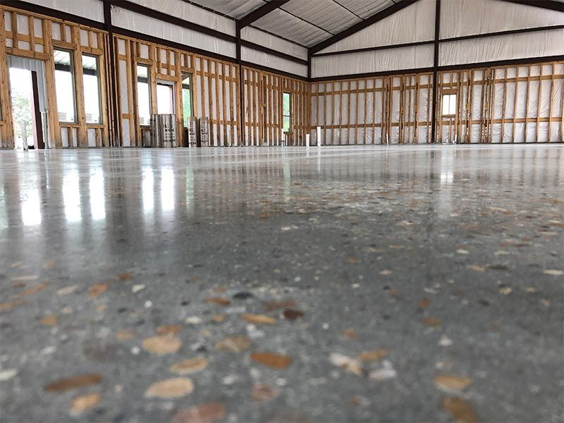 Empty unfinished room with exposed framing and a polished concrete floor