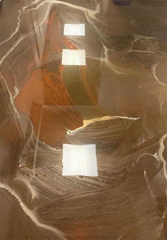 Aerial view of a brown desert landscape with three white rectangular structures aligned vertically.