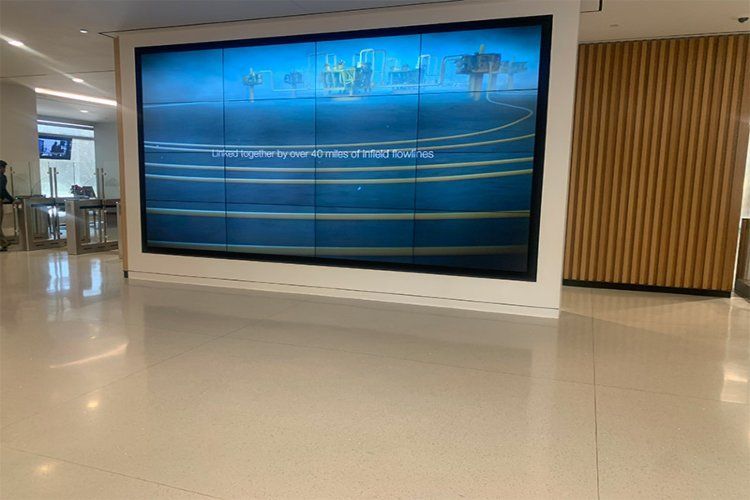 Modern lobby with a large blue digital display wall and polished white floor