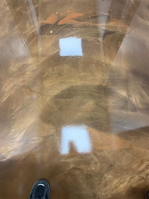 Shiny brown floor reflecting overhead lights, with a shoe tip visible at the bottom edge.