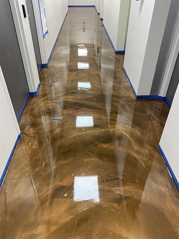 Shiny brown hallway floor with white walls and blue trim, reflecting overhead lights.
