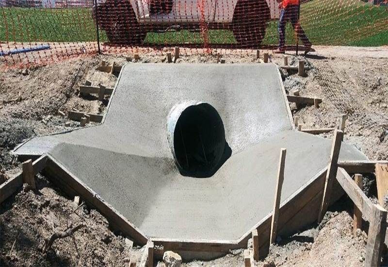 Concrete drainage culvert under construction with workers in the background