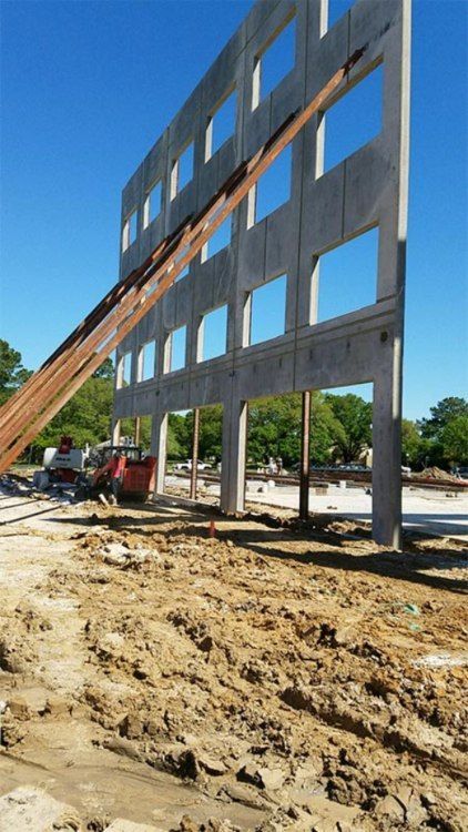 Partially built concrete structure at a construction site with workers and scaffolding ramp