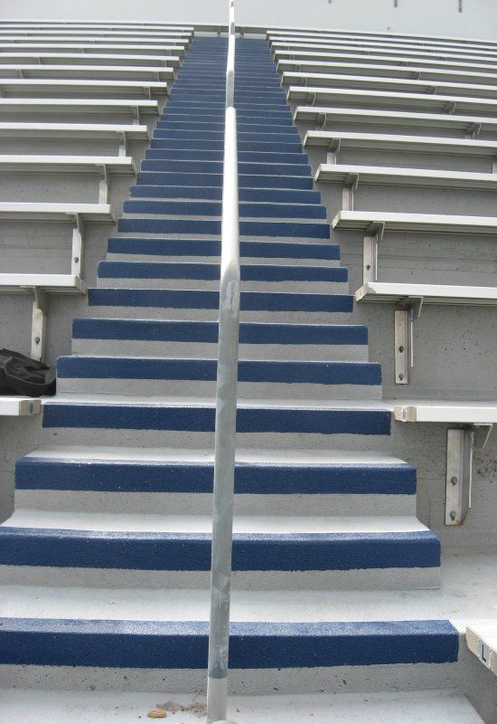 Blue carpeted stadium stairs leading up between rows of white bleachers