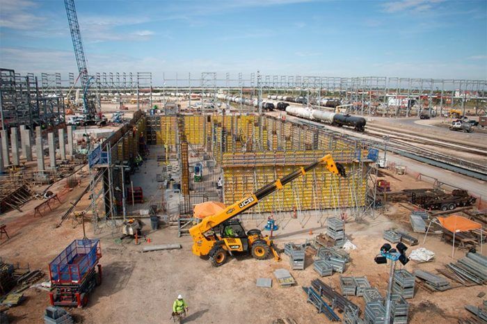 Construction site with cranes, scaffolding, and heavy machinery on a large industrial project.
