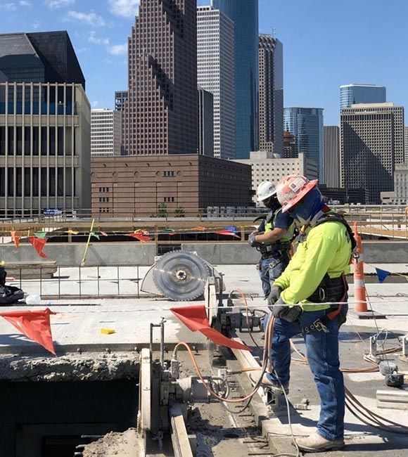 Construction worker in neon jacket and hard hat standing at a city jobsite with skyline behind him