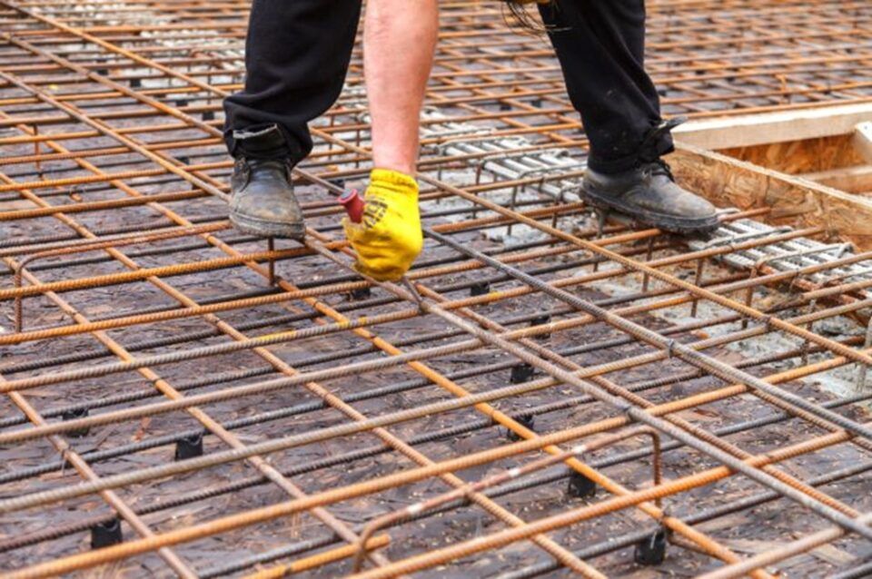 An individual in yellow gloves stands on a steel grid, representing a work site in TX and LA