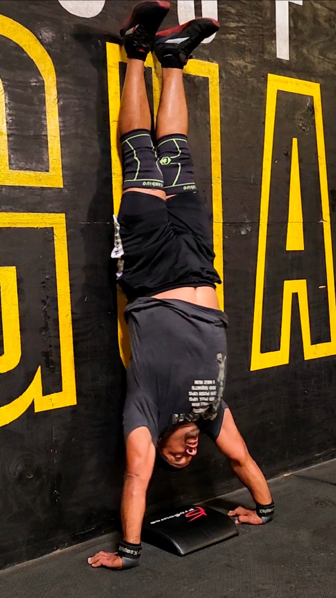 Four people standing in front of a CrossFit Jaguar in Tampa,FL wall mural, wearing athletic clothes in black, pink, purple, and red.