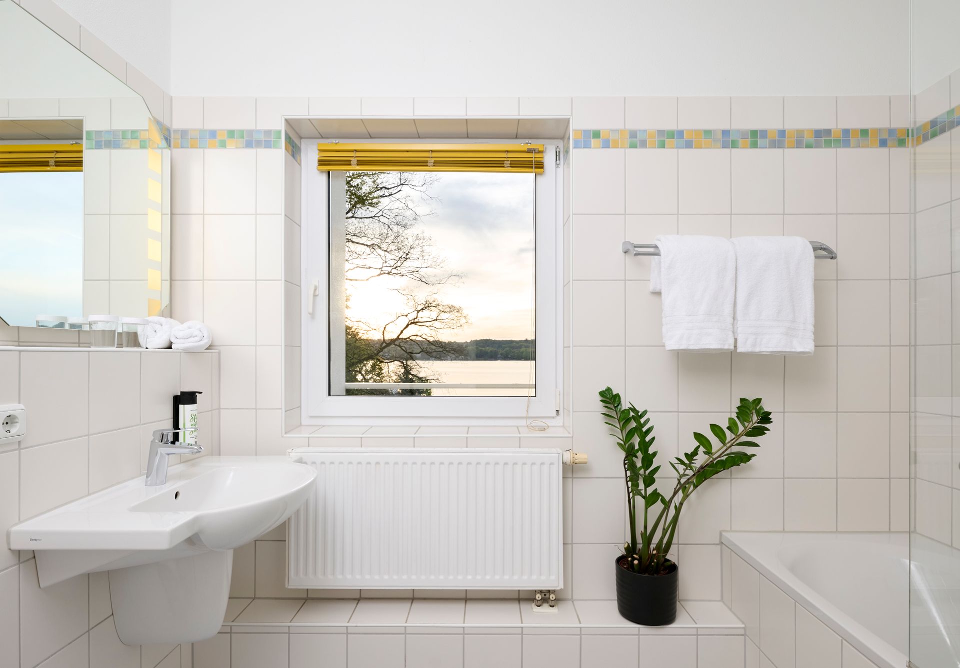 Modernes Badezimmer mit hellen Fliesen und Fenster im Hotel Schloss Berg.
