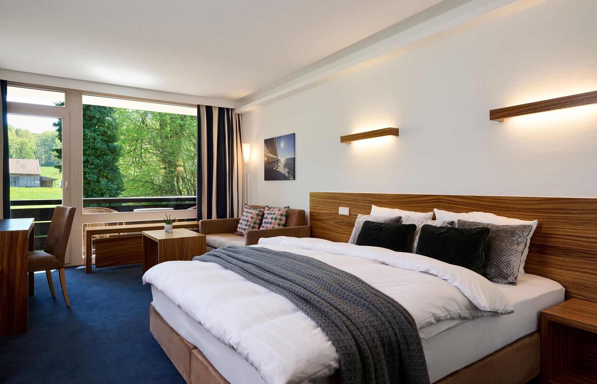Helles Hotelzimmer am Starnberger See mit Doppelbett und stilvoller Einrichtung.