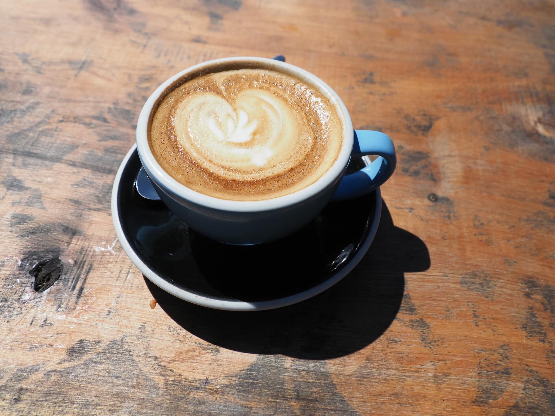 Eine Tasse Cappuccino auf einer Untertasse auf einem Holztisch.