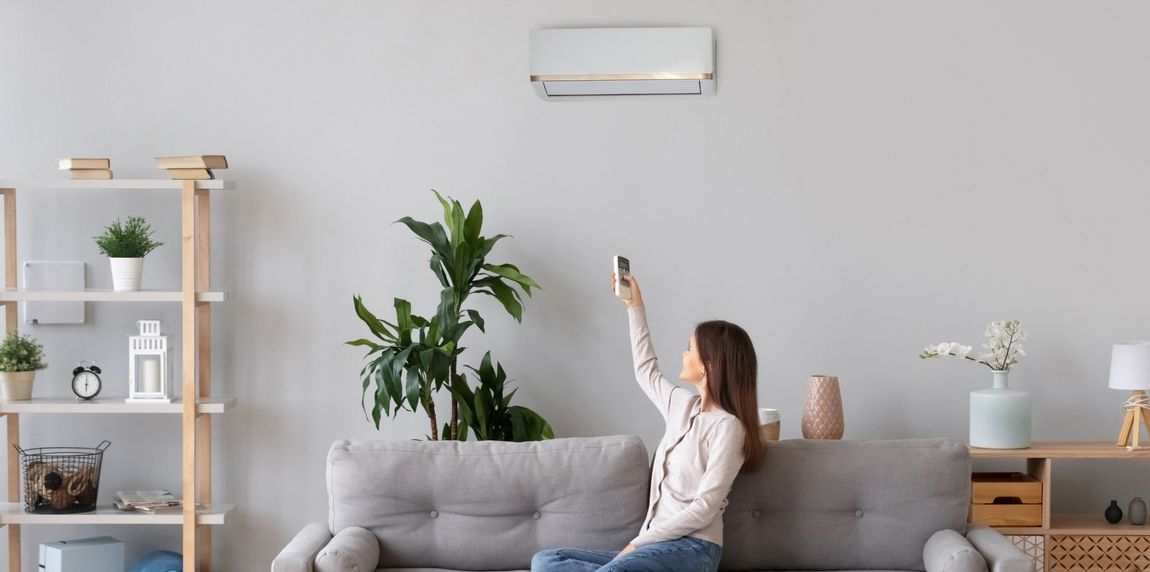 Woman Switching On Air Conditioner — West Ivins, UT — Airco Heating & Cooling Inc Woman Switching On Air Conditioner — West Ivins, UT — Airco Heating & Cooling Inc