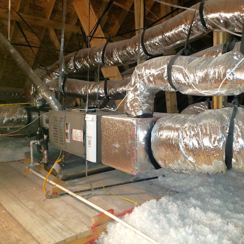 Insulated HVAC ductwork and furnace in a crawl space with exposed attic framing.
