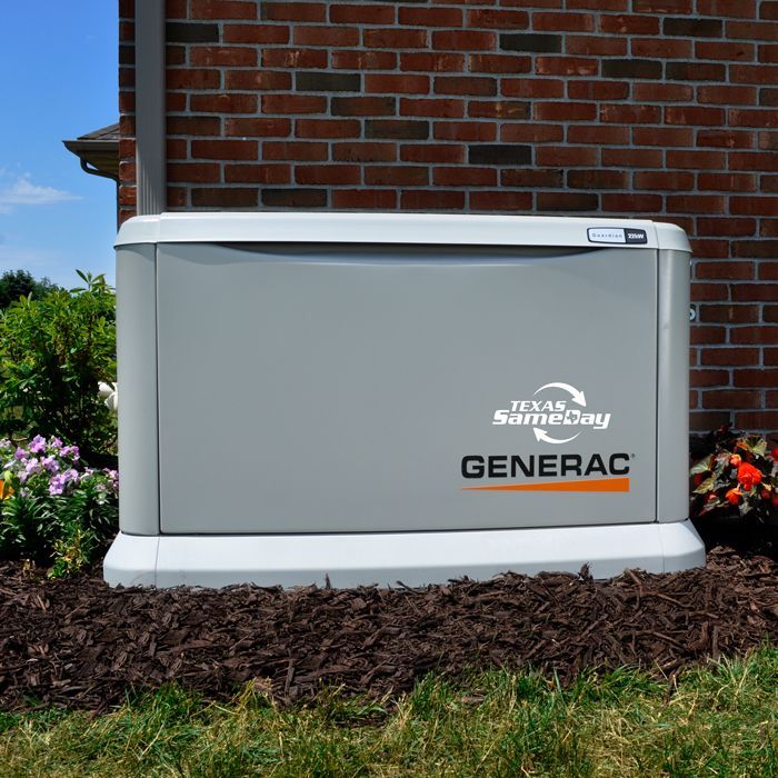 Gray Generac standby generator beside a brick house with landscaping