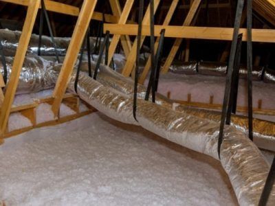 Attic with insulated HVAC ducts and exposed wooden trusses