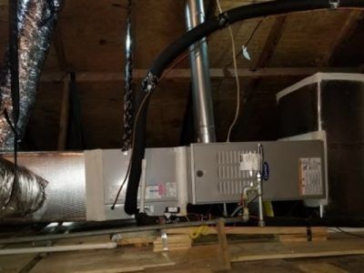 Water heater and ductwork installed in an unfinished attic with exposed beams and insulation
