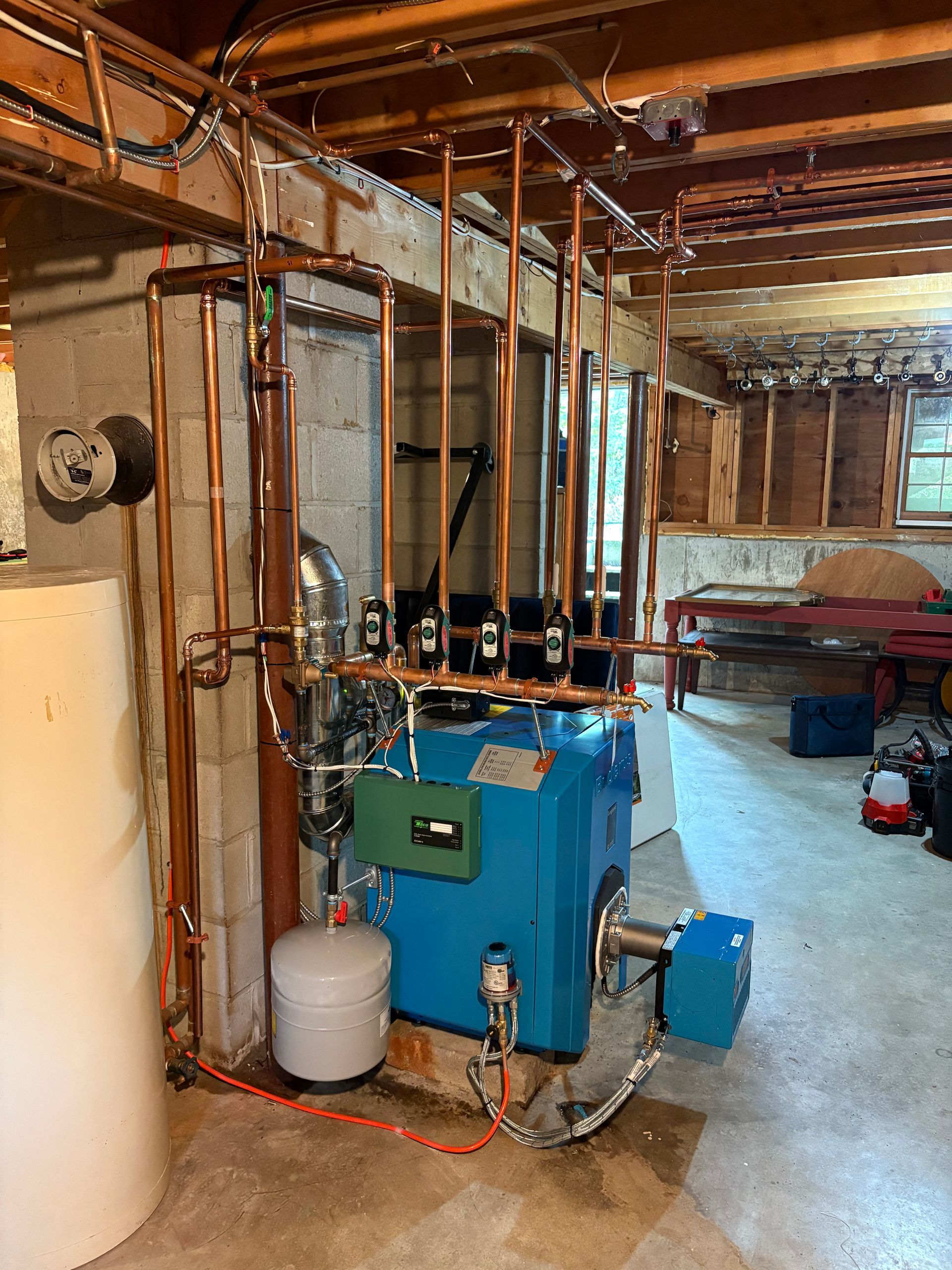 Blue boiler with copper pipes in a basement setting.