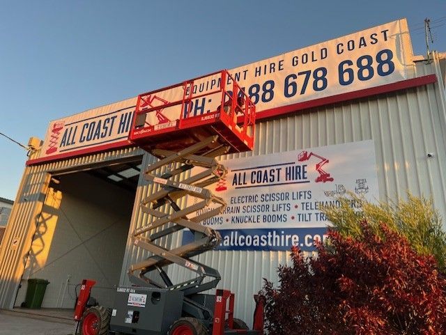 A red scissor lift is extended in front of an 