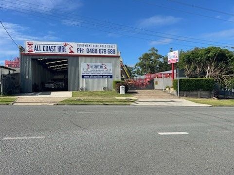 An exterior view of an All Coast Hire building and equipment yard under a bright, blue sky on a sunny day.