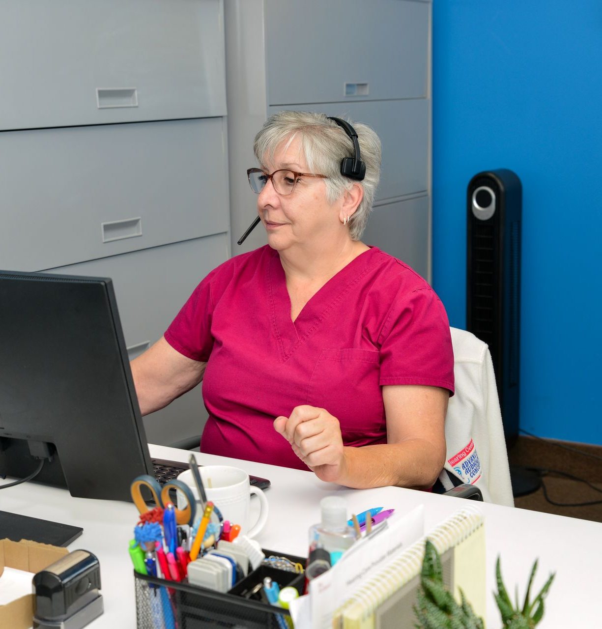 Caretaker adjusting an older person's hearing aid in a bright indoor setting