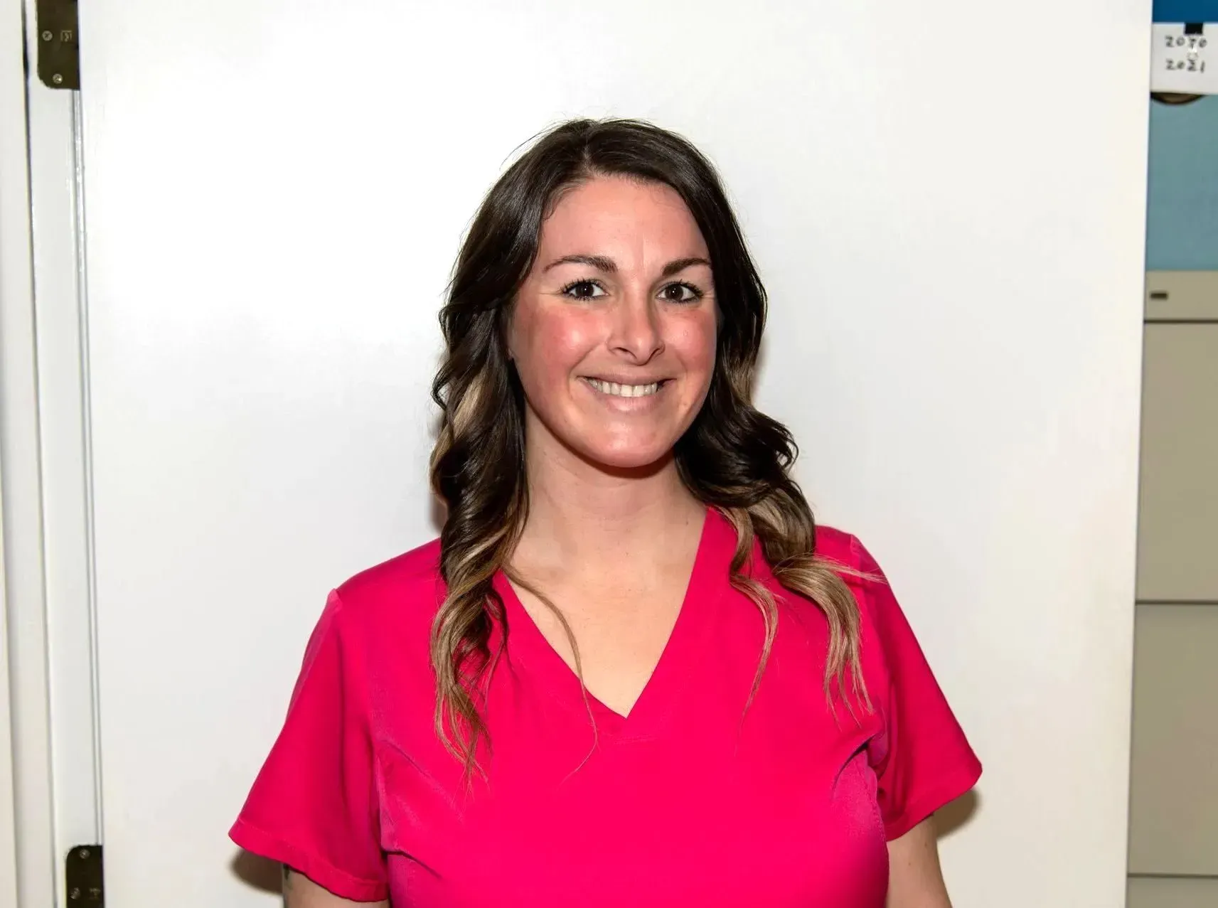 Woman smiling in a bright pink top against a white background