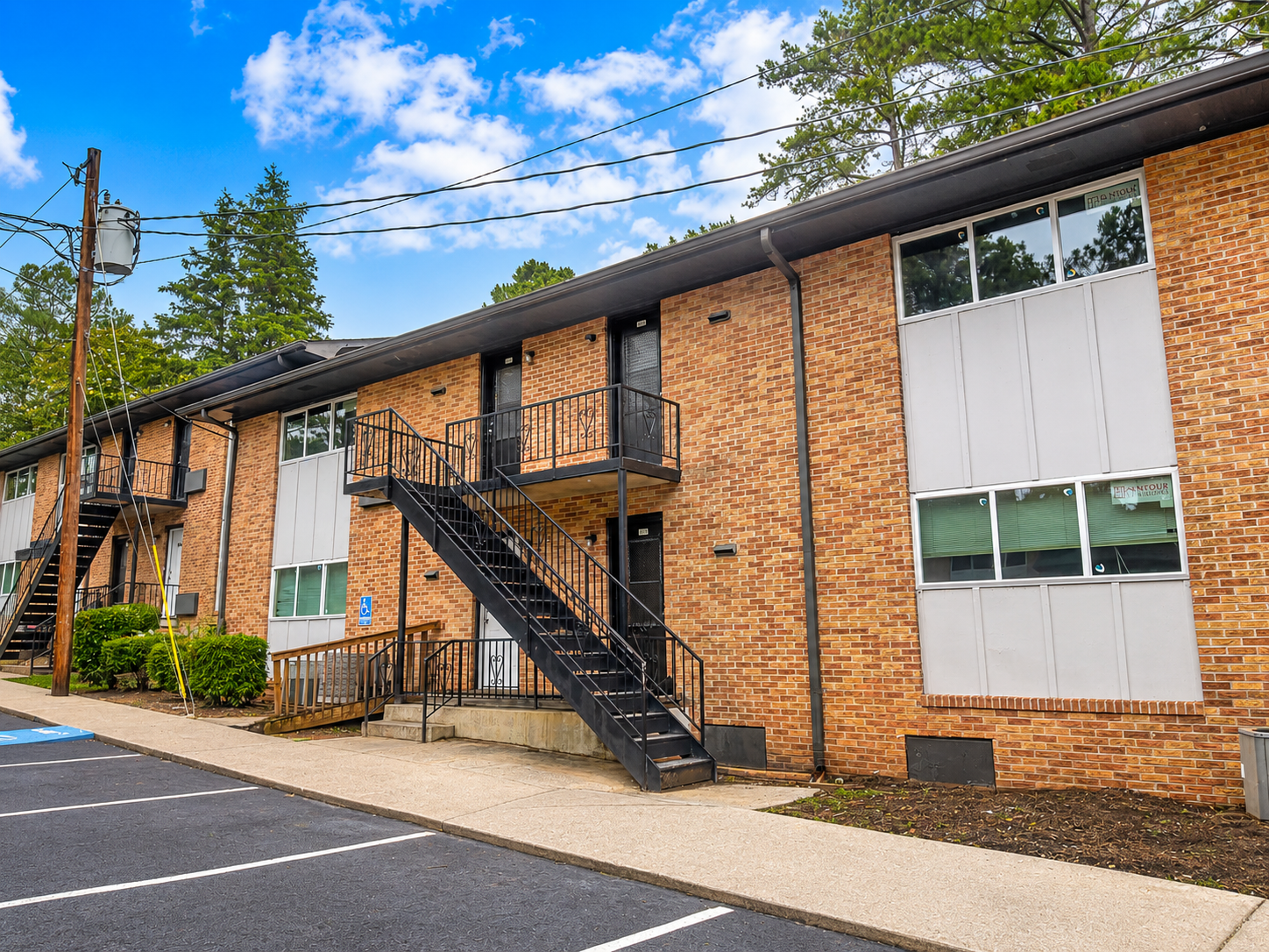 Chat GPT Image of a two-story apartment building  with a partially cloudy sky in the background
