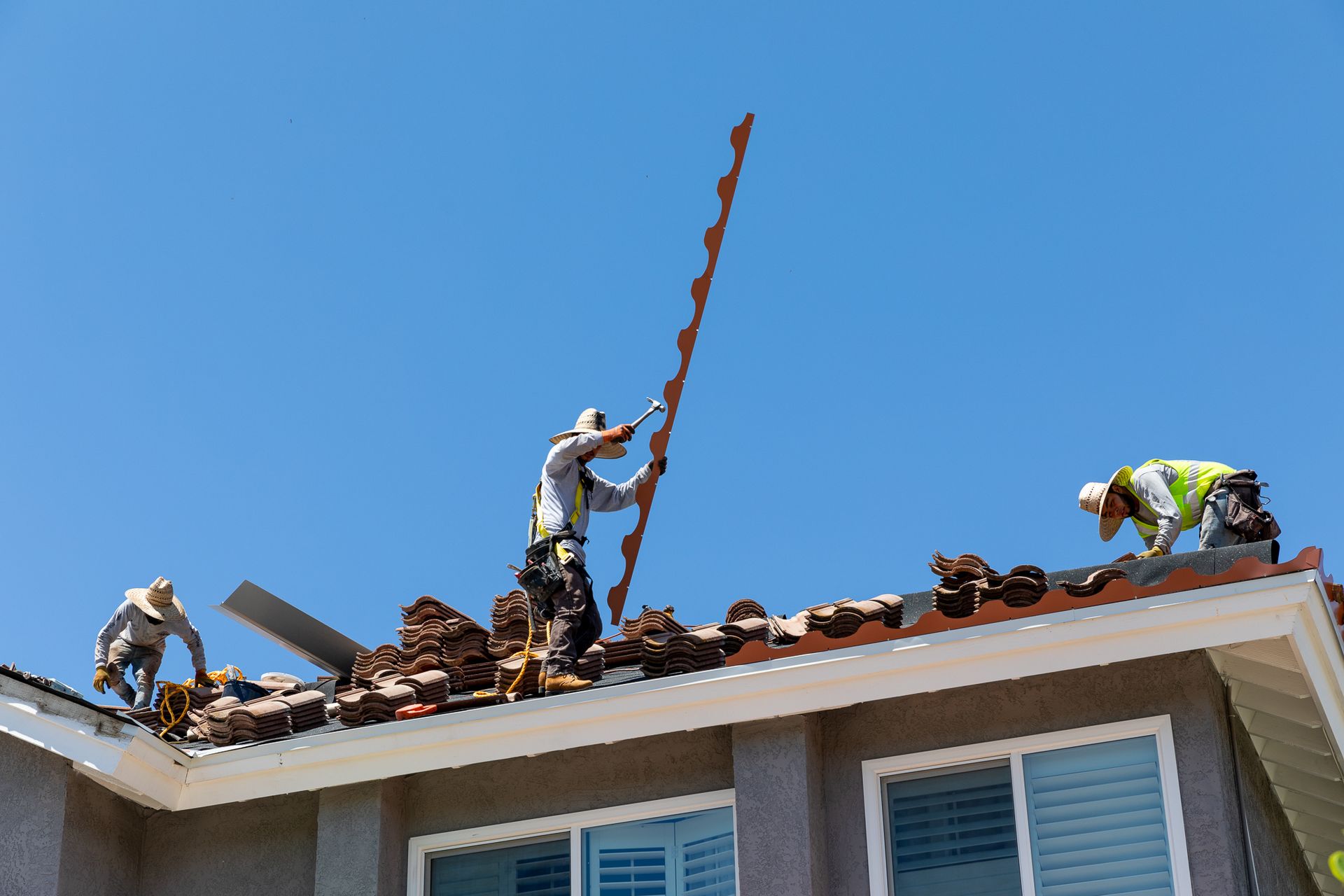 Two men are working on the roof of a house