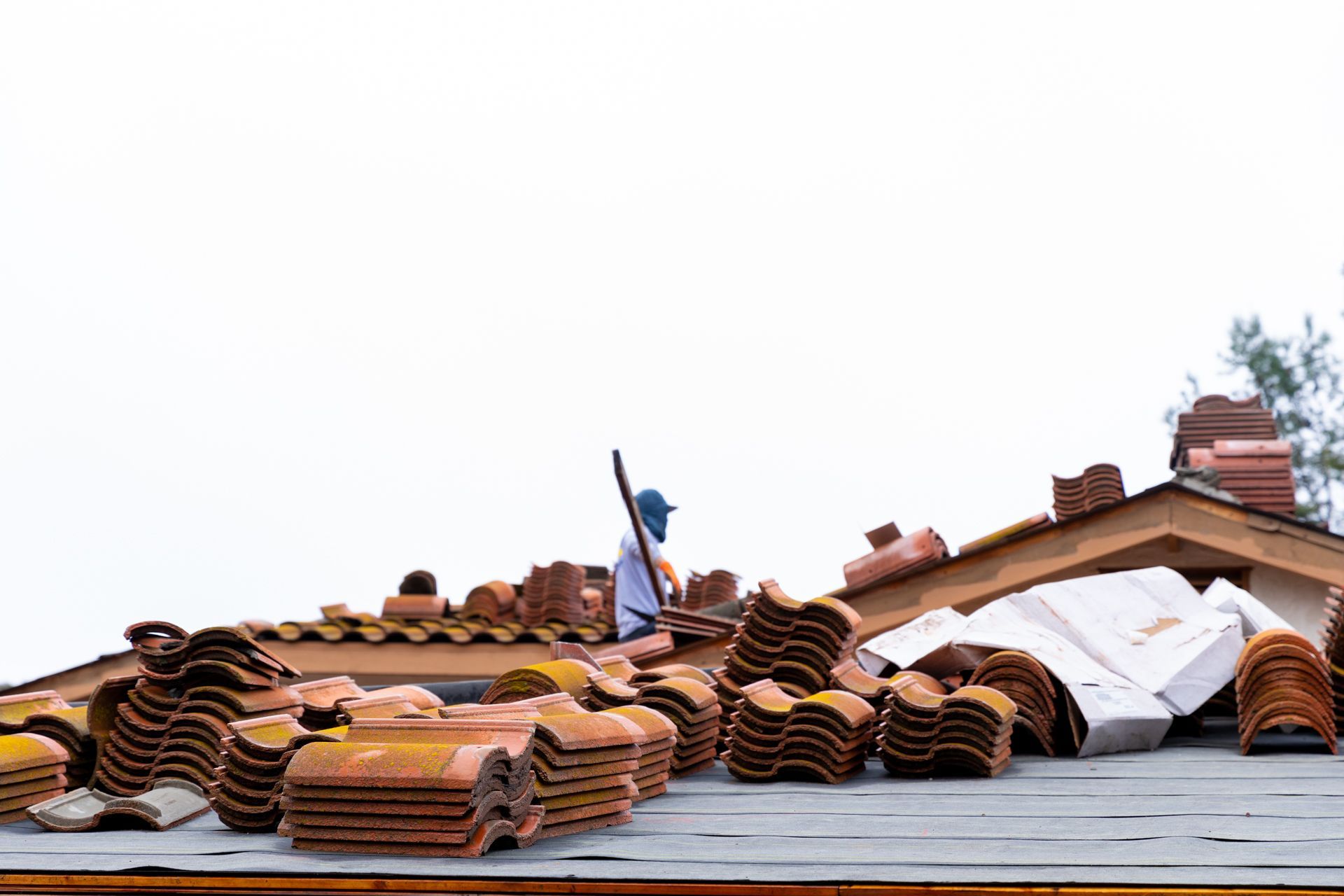 A man is standing on top of a pile of roof tiles