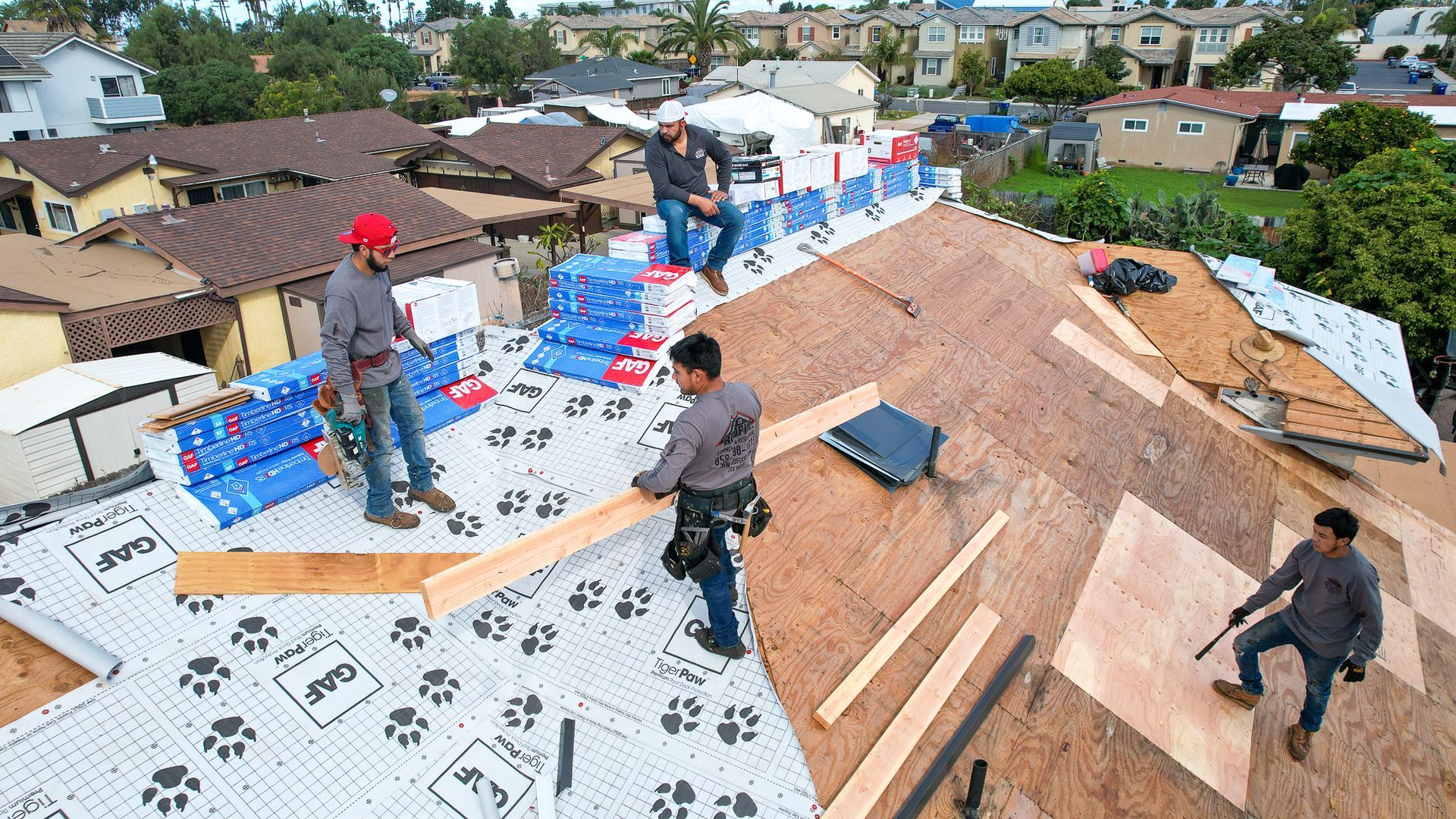 A group of men are working on the roof of a house