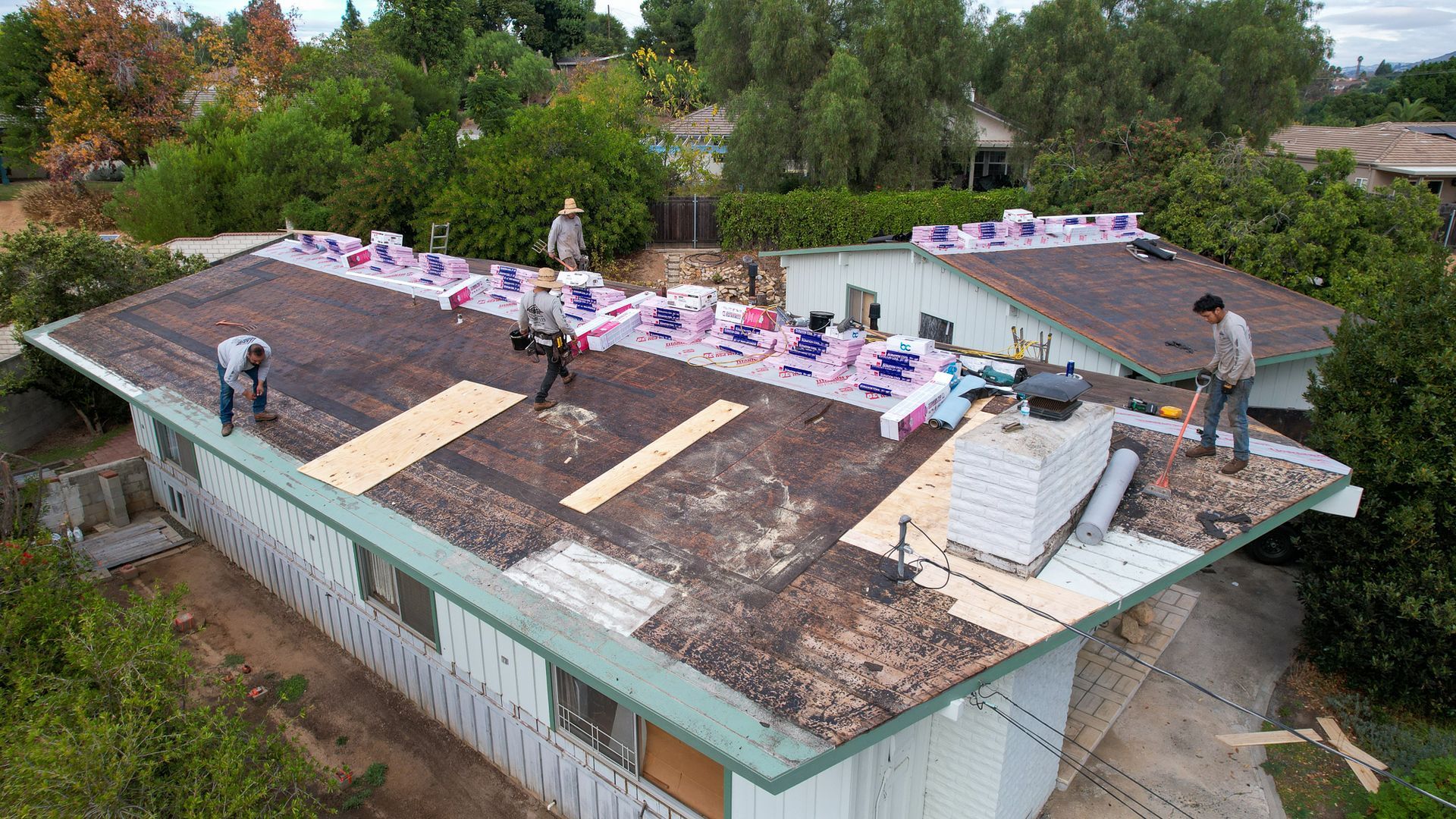 A group of men are working on the roof of a house