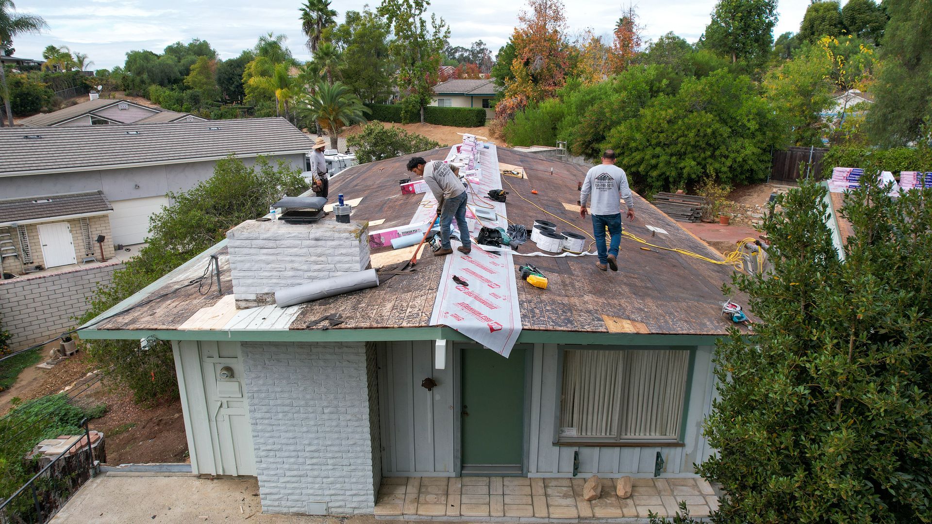 A group of people are working on the roof of a house