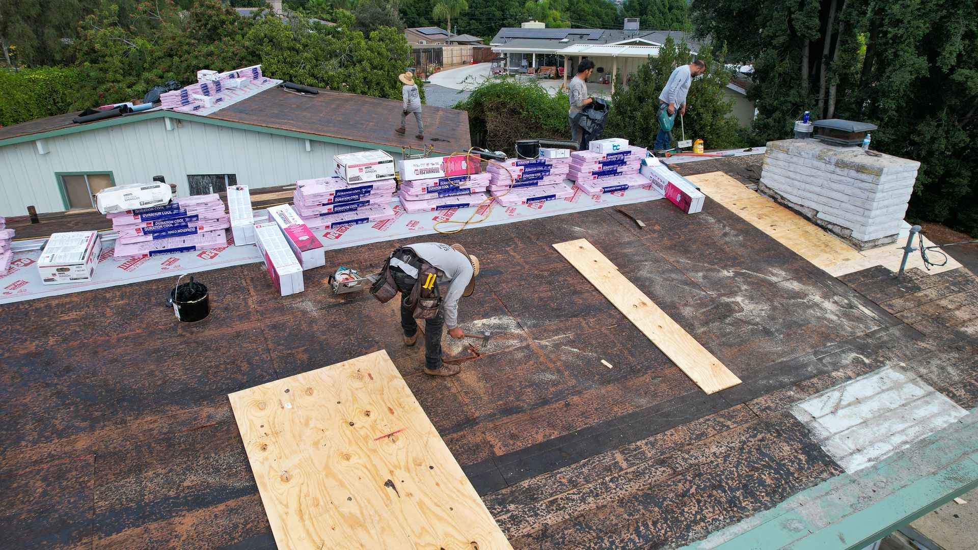 Two men are working on the roof of a house