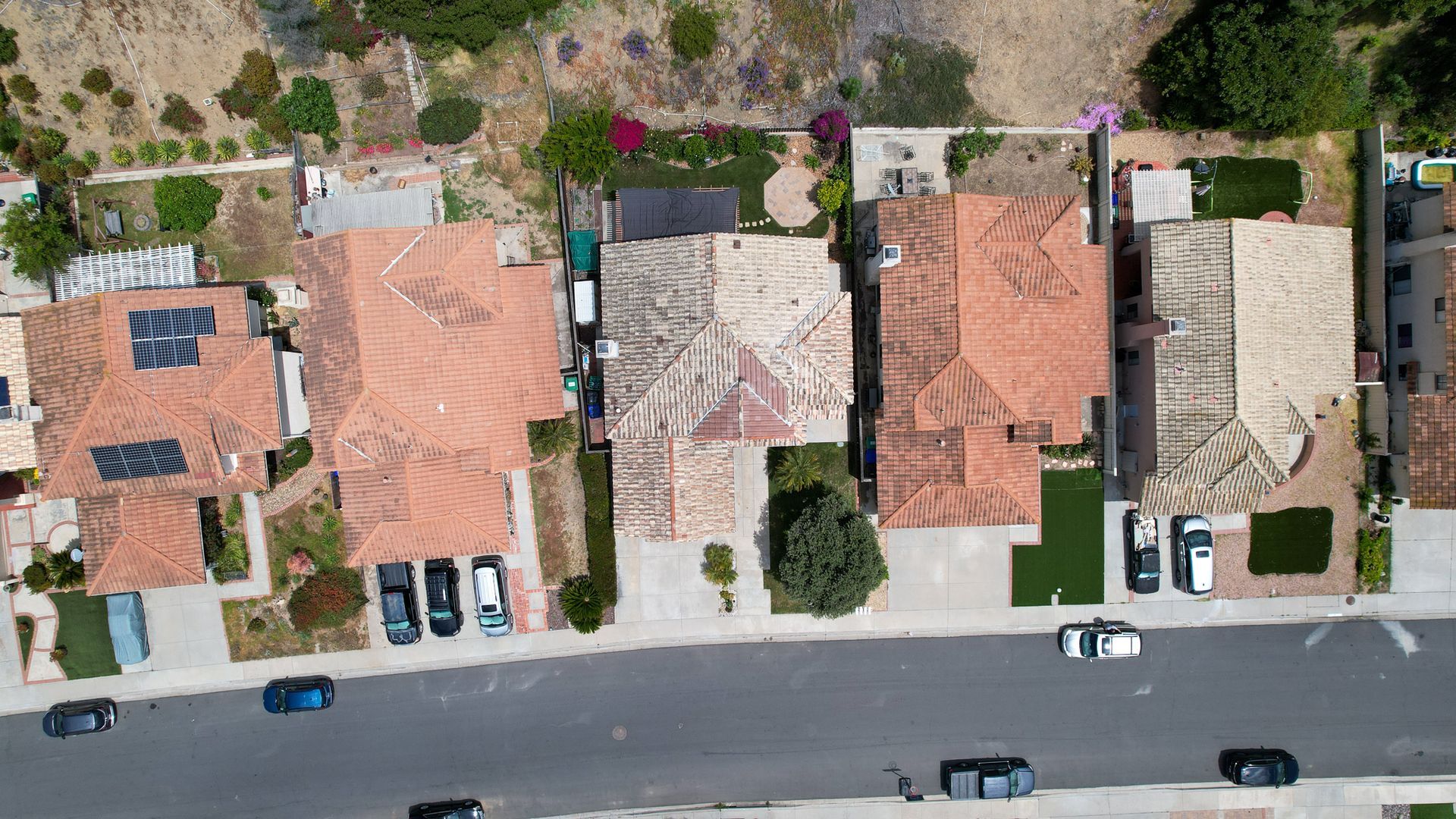 An aerial view of a residential area with cars parked on the side of the road