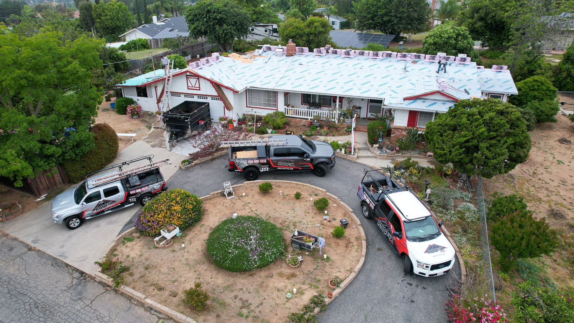 An aerial view of a house with trucks parked in front of it