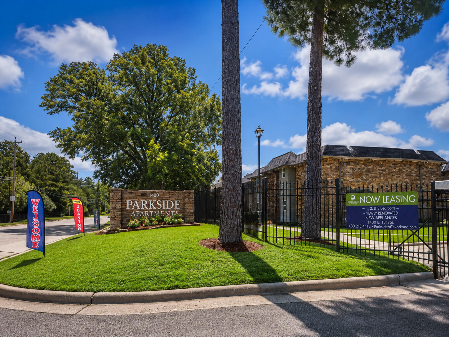 Entrance sign for Pheasant Run apartments with green lawn, palm trees, and blue sky