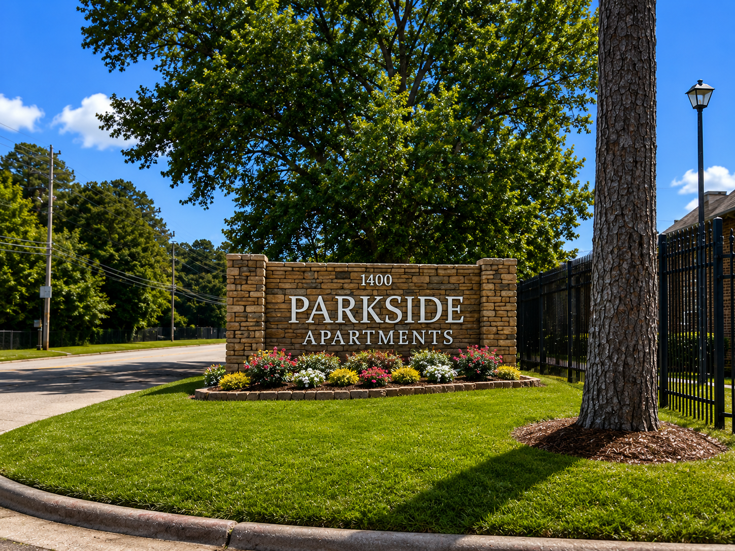 Parkside Apartments stone entrance sign beside a manicured lawn and trees on a sunny day