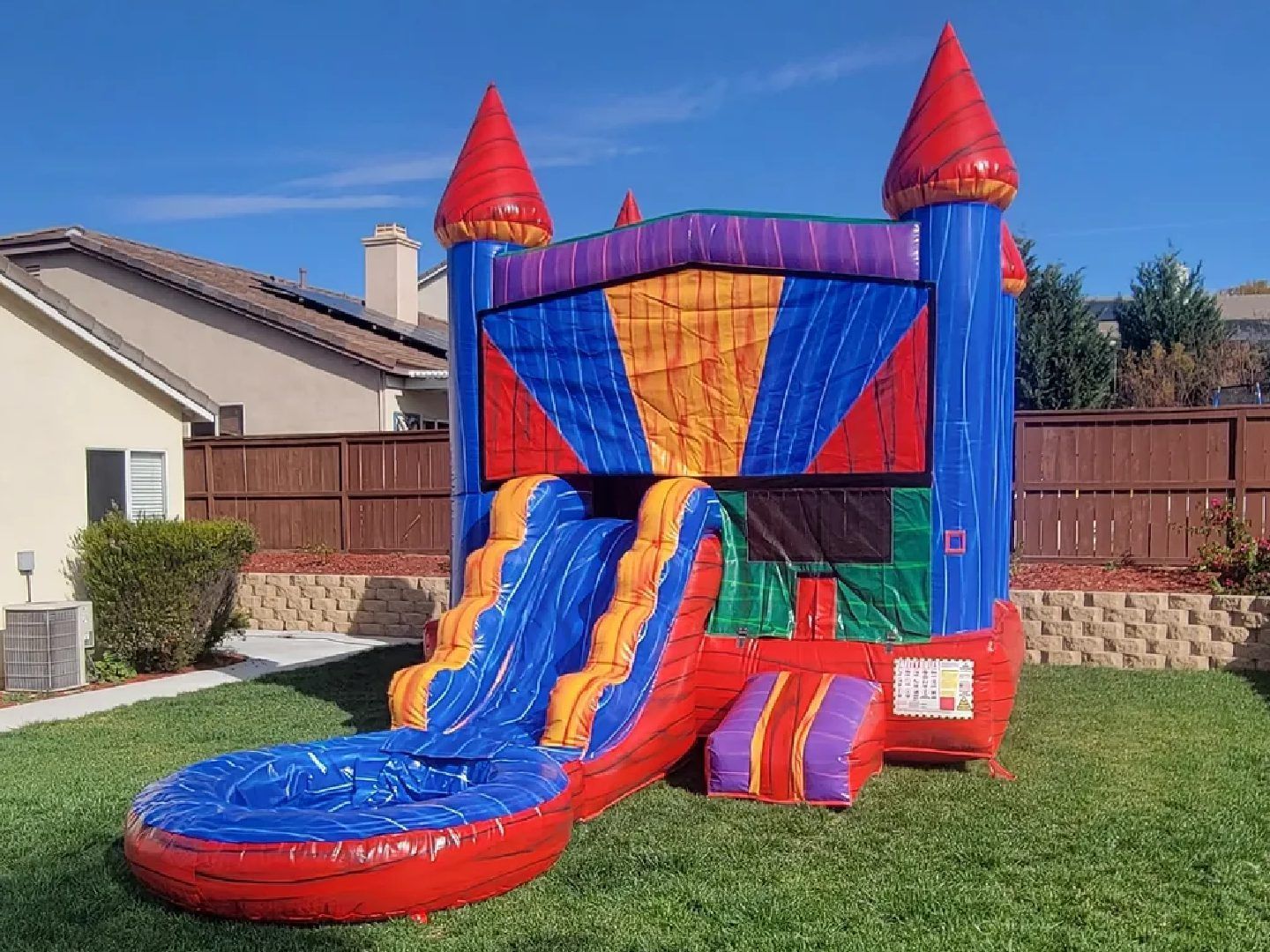 Colorful inflatable castle bounce house with slides in a sunny backyard