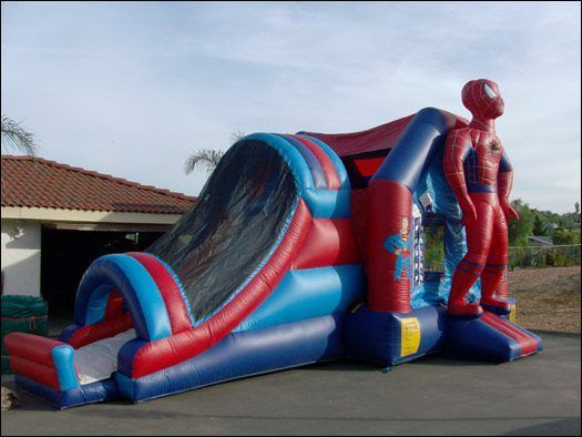 Red and blue Spider-Man inflatable slide on a paved lot beside a building